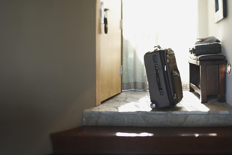 Suitcase in doorway Photograph by Jupiterimages
