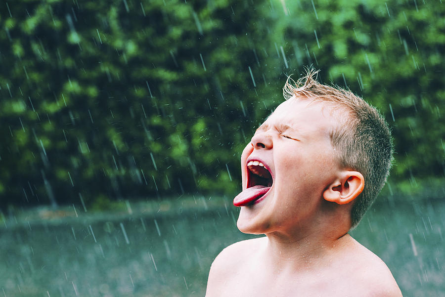Summer rain pours and boy tastes the raindrops Photograph by Mikkelwilliam