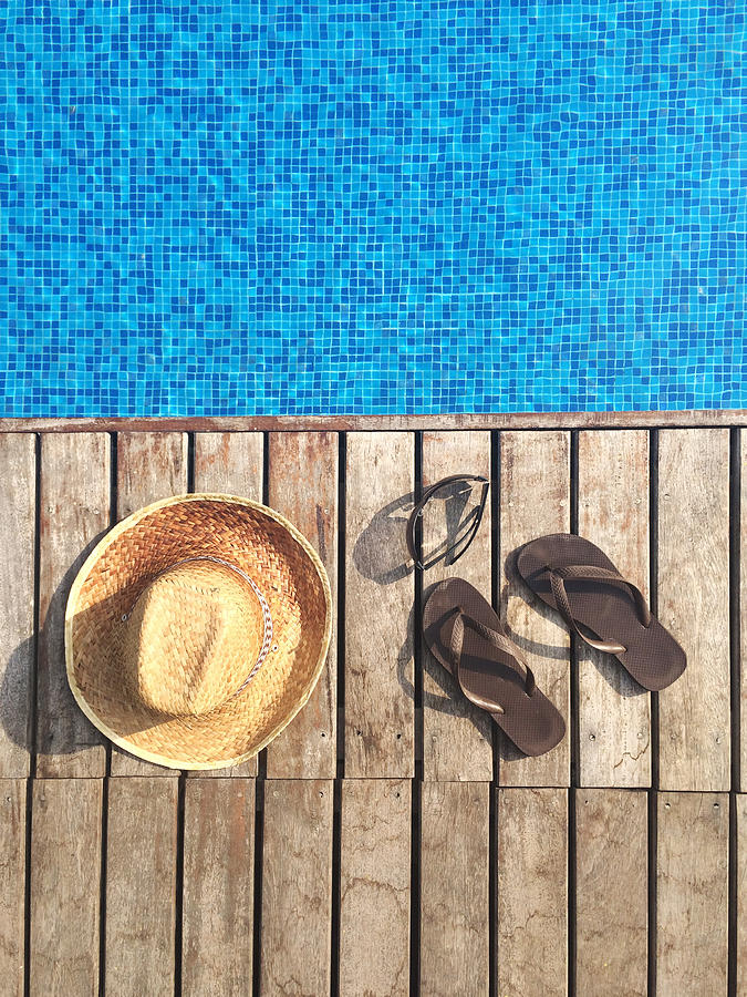 Sun hat, flip-flops and sunglasses by swimming pool Photograph by Alfiecain