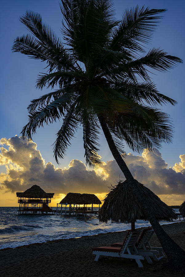 Sunrise at the beach with silhouette of pier with thatched huts Photograph by OGphoto