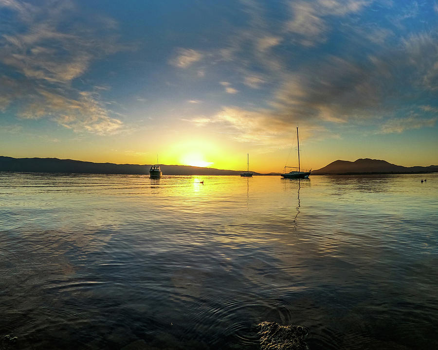 Sunrise over the lake with sailboats in the foreground Photograph by Devin Wilson