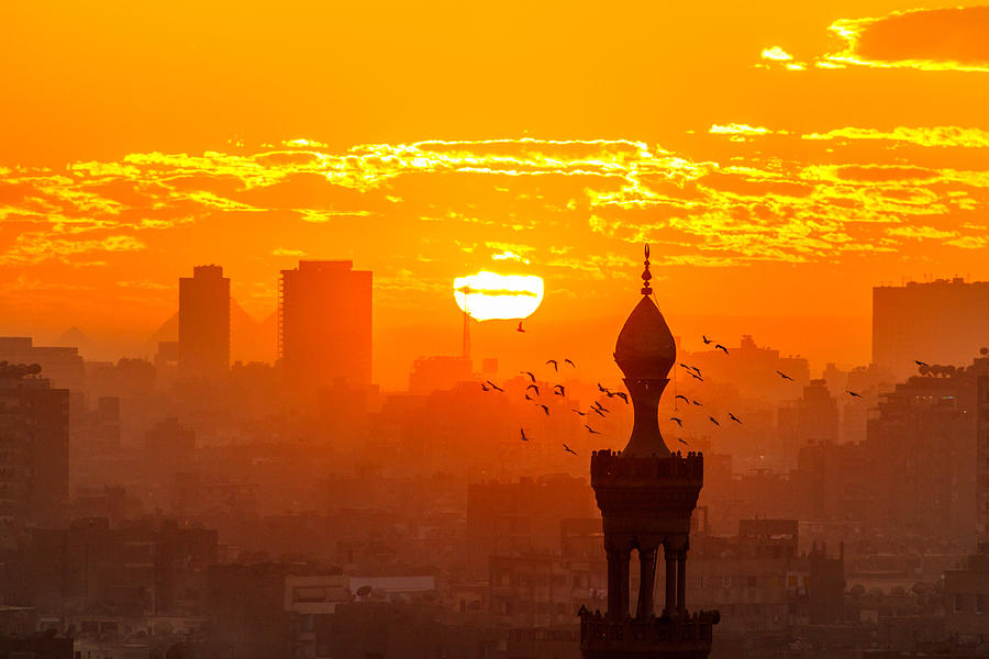 Sunset in Cairo from Al-Azhar Garden, Egypt. The Pyramids behind two buildings in background Photograph by Loïc Lagarde