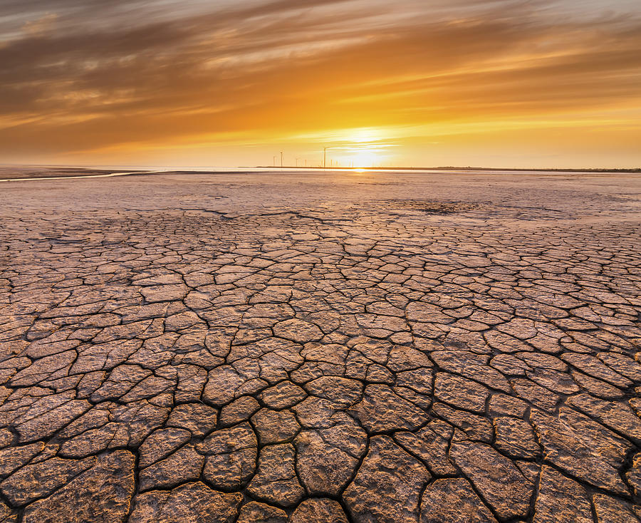 Sunset over cracked soil in the desert. Global warming concept Photograph by Anton Petrus