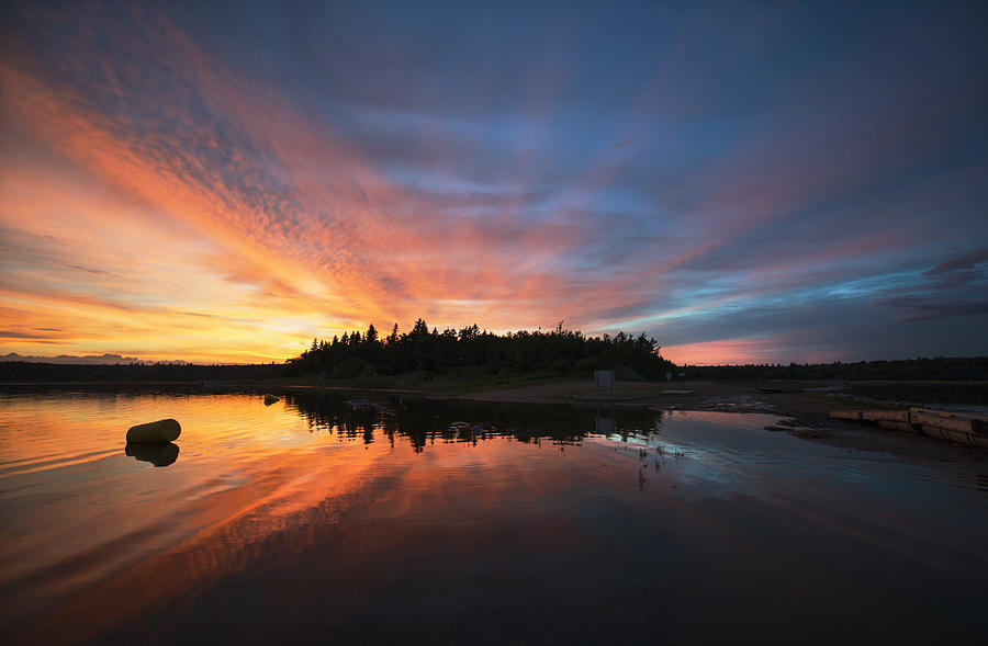 Sunset sky reflected in a lake, and clouds in the sky. Photograph by Mint Images