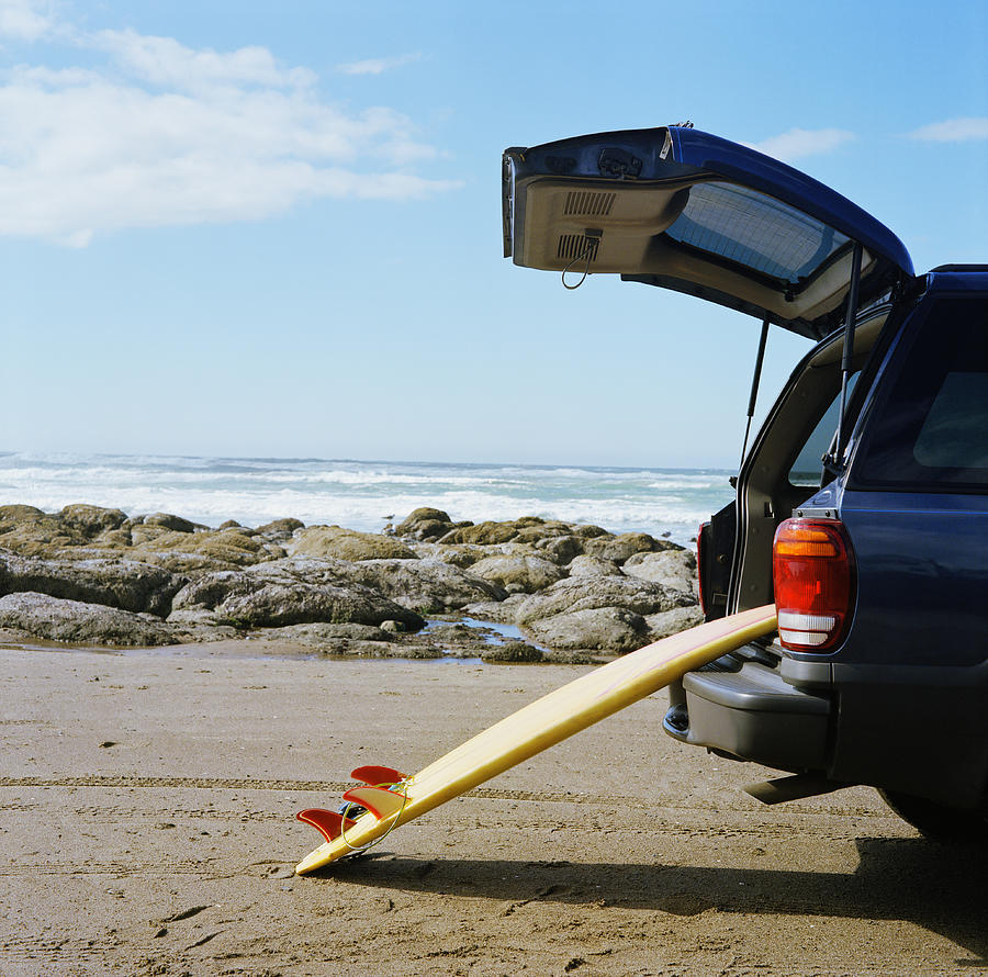 Surfboard leaning against open boot of SUV on beach Photograph by Bryan Mullennix
