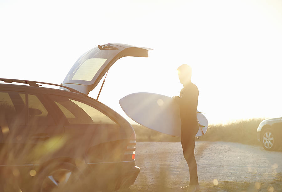 Surfer taking surfboard out of car. Photograph by Dougal Waters