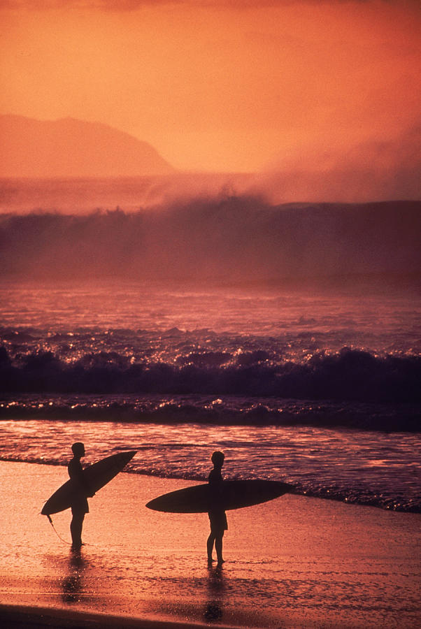 Surfers at sunset, Oahu, Hawaii Photograph by Bill Romerhaus