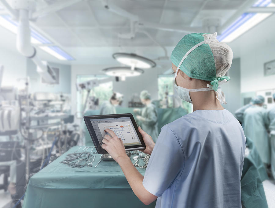 Surgeon using digital tablet Photograph by Thierry Dosogne
