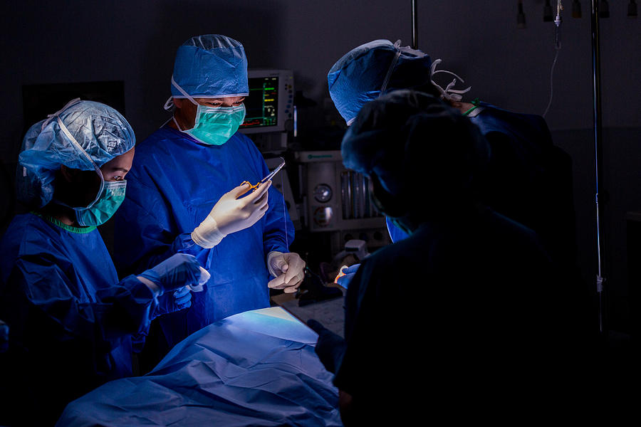 Surgeon using sutures during operation in hospital operating room Photograph by SDI Productions