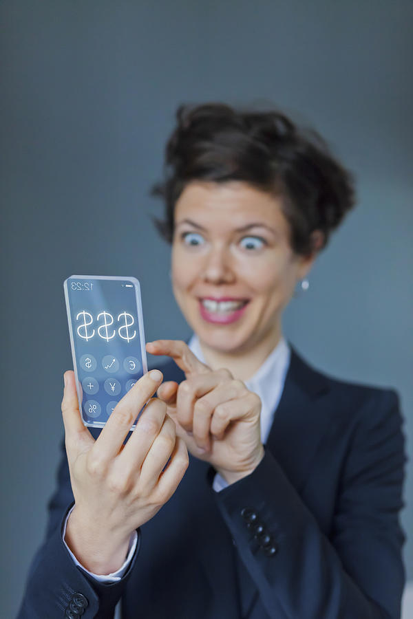 Surprised Businesswoman Using Futuristic Transparent Mobile With Dollar Sign Photograph by Ralf Hiemisch
