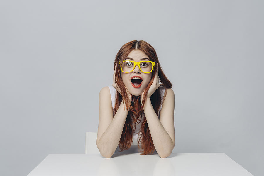 Surprised Caucasian woman sitting at table wearing yellow eyeglasses Photograph by Dmitry Ageev