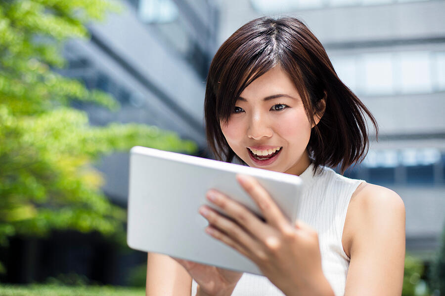 Surprised Japanese businesswoman looking at digital tablet Photograph by Xavierarnau