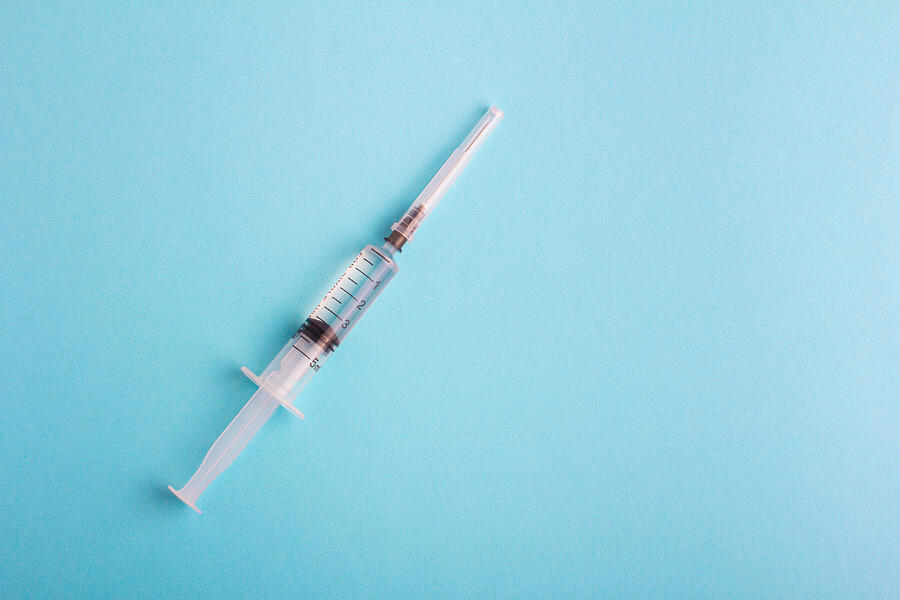 Syringe with lid on blue background Photograph by Dan Meshkov