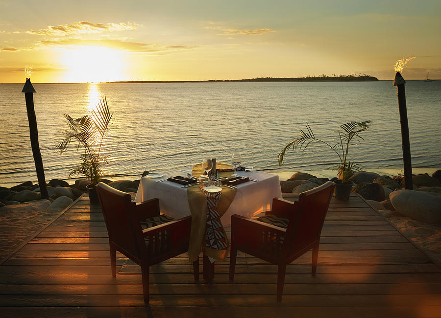 Table and chairs on waterfront at sunset Photograph by Colin Anderson Productions pty ltd