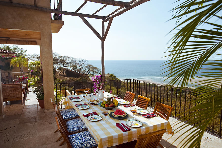 Table set for meal on patio, Pacific Ocean view Photograph by Wayne Eastep