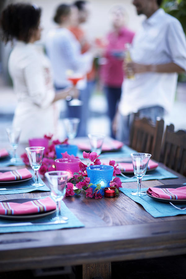 Table setting for dinner party, people standing in background Photograph by Maren Caruso