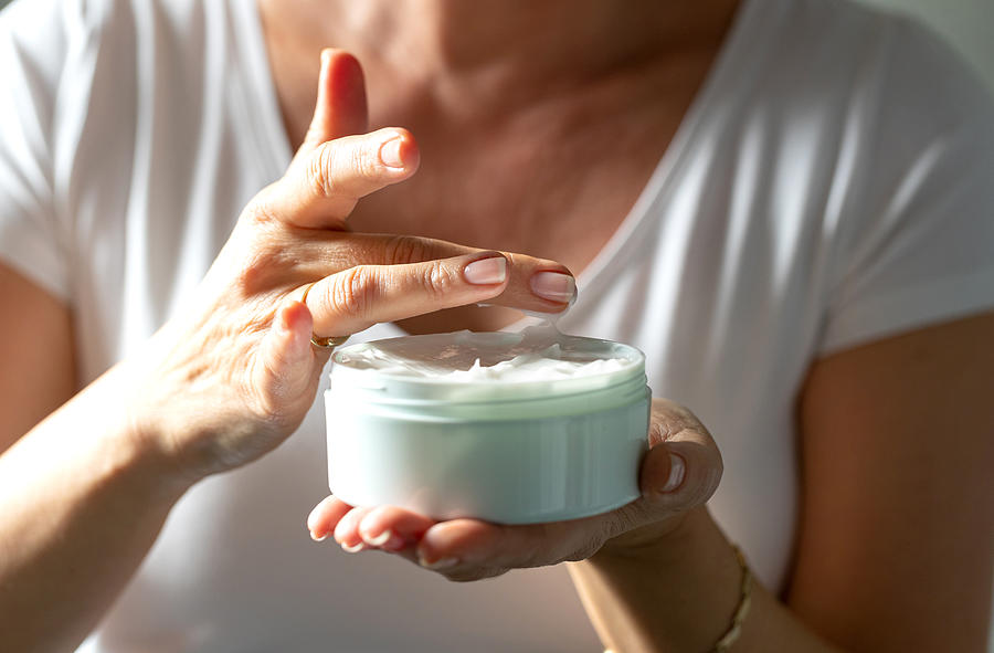 Taking facial cream with finger from a jar Photograph by Zoranm