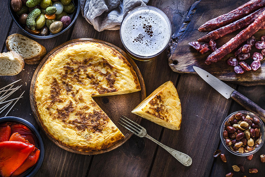 Tapas: spanish tortilla, chorizo, pimientos, olives and beer shot from above Photograph by Fcafotodigital