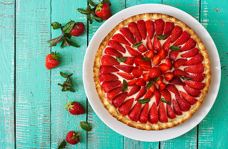 Tart with strawberries and whipped cream decorated with mint leaves. Photograph by Elena_Danileiko