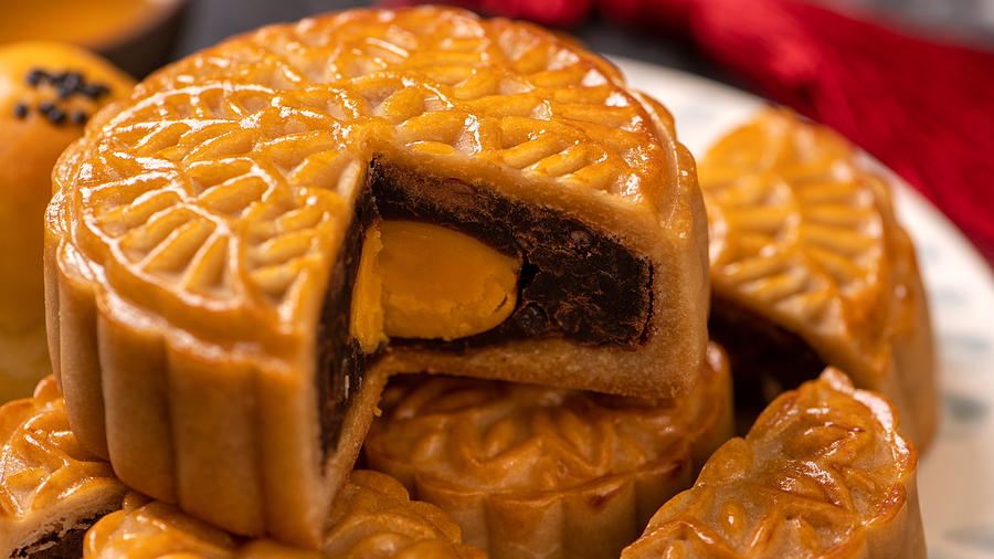 Tasty baked egg yolk pastry moon cake for Mid-Autumn Festival on black slate dark background. Chinese festive food concept, close up, copy space. Photograph by Insjoy
