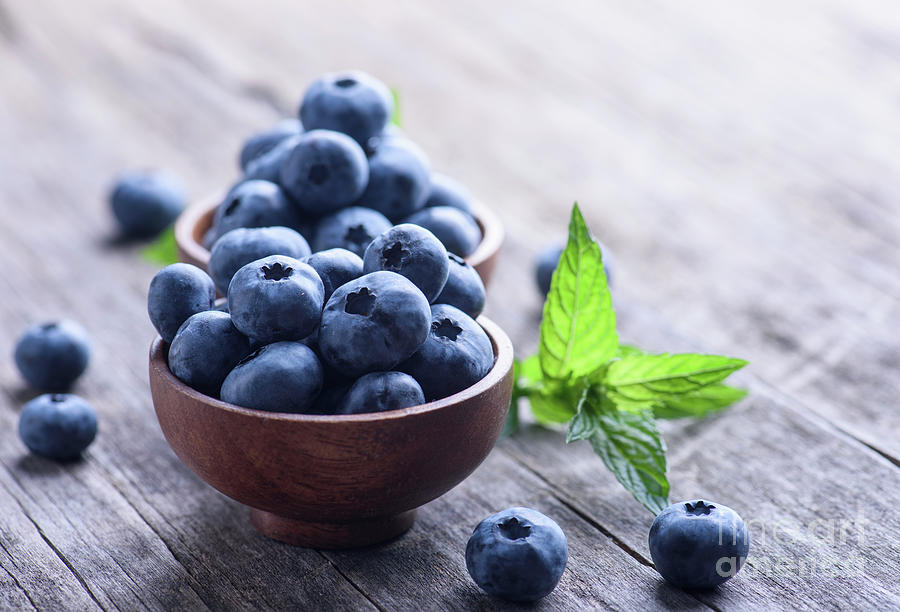 Tasty blueberries in wooden bowl on rustic table background Photograph by Jelena Jovanovic