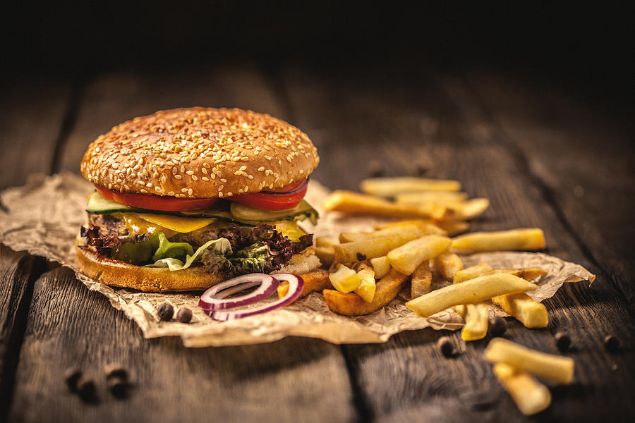 Tasty hamburger with french fries on wooden table Photograph by Da-kuk