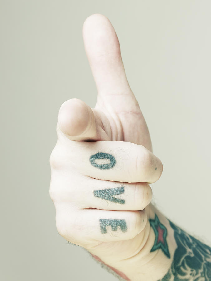 Tattooed hand making gun shaped gesture. Photograph by Ballyscanlon