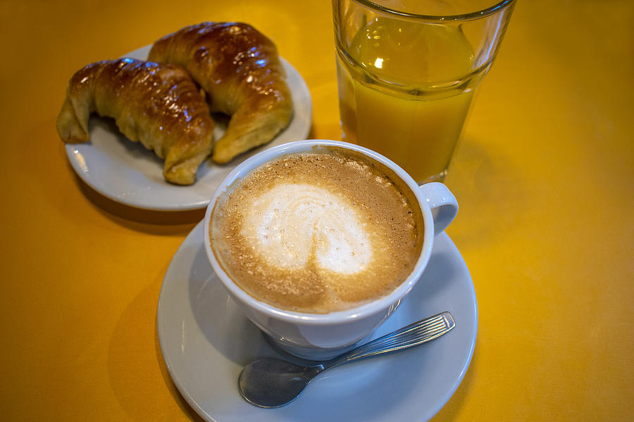 Taza de café con leche, medialunas de manteca y vaso de jugo de naranja exprimido Photograph by Javier Ghersi
