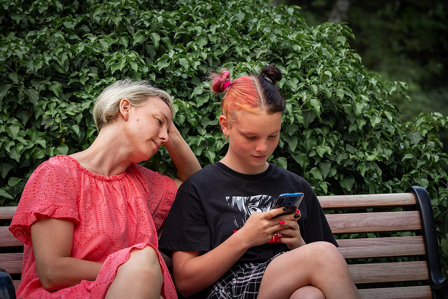 Teen girl holding mobile phone and looking at the screen. Problems of Diverse Generations. Youth culture Photograph by Rbkomar