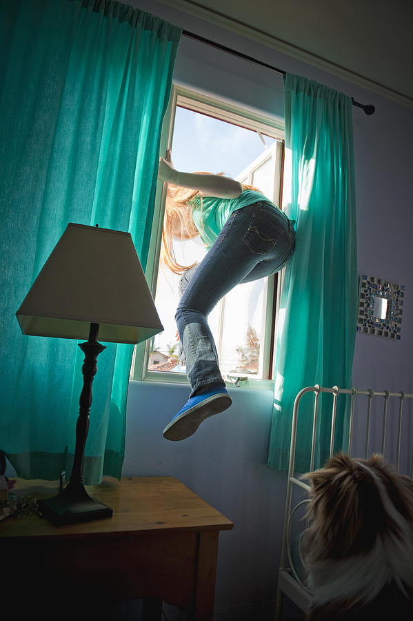 Teen Girl Sneaking Out Her Bedroom Window Photograph by Stephen Simpson