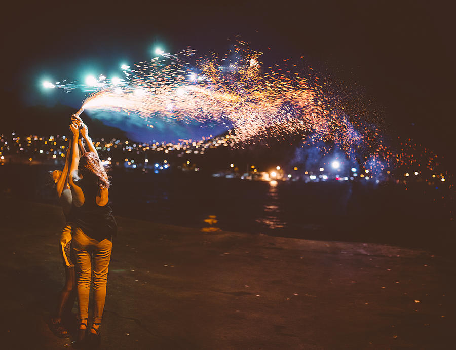 Teen girls holding sparkling fireworks at night at the harbour Photograph by Wundervisuals