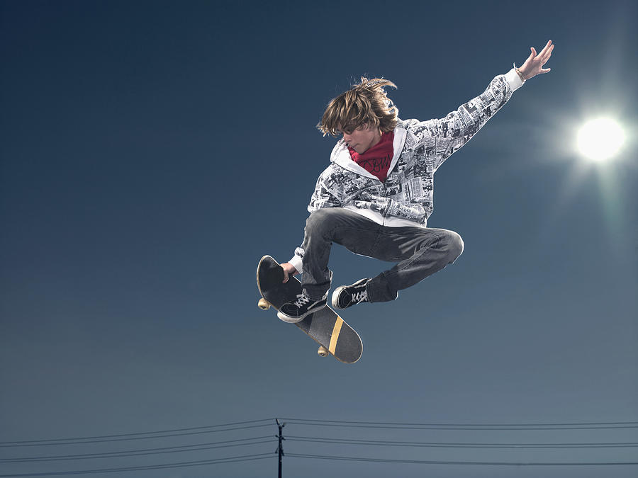 Teenage boy (16-17) performing jump on skateboard, low angle view Photograph by Siri Stafford