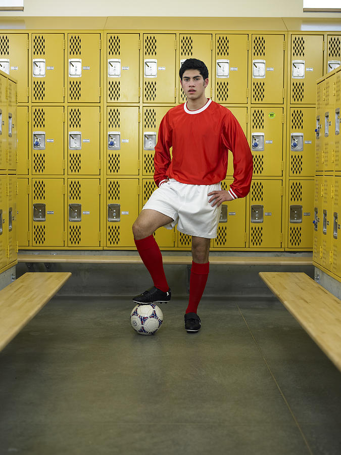 Teenage boy (16-18) dressed for soccer, standing in locker room Photograph by Thomas Barwick