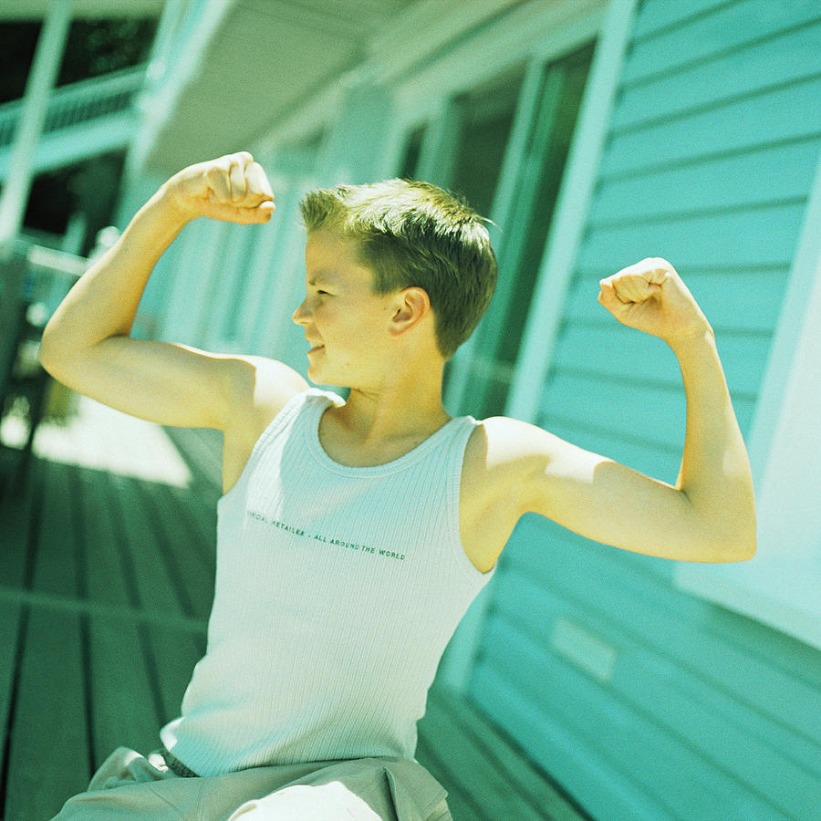 Teenage boy flexing arm muscles Photograph by Patrick Sheandell OCarroll