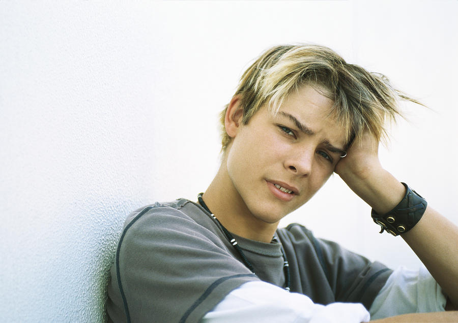 Teenage boy holding head, looking at camera Photograph by Sigrid Olsson