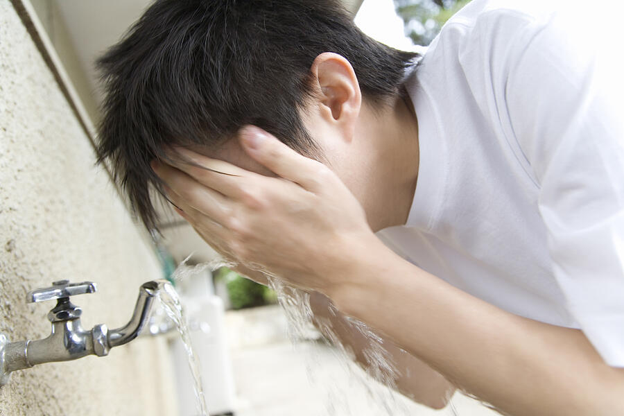 Teenage boy in gym cloth washing face, blurred motion Photograph by Daj