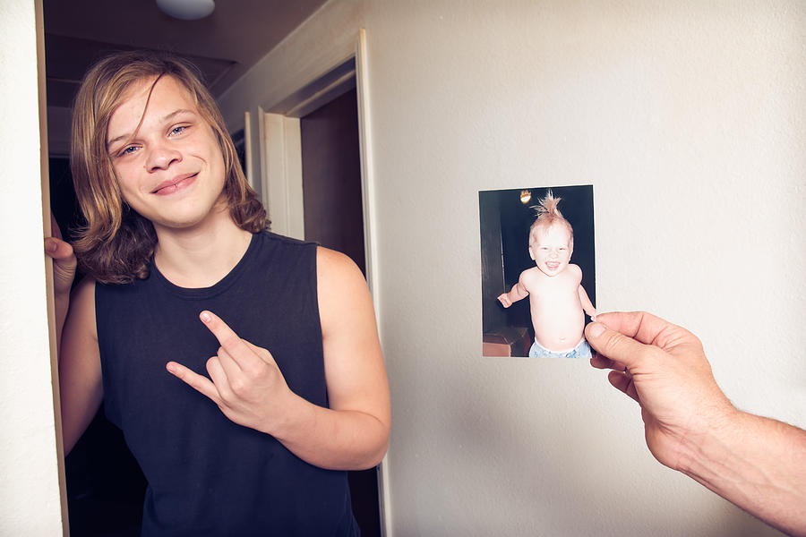 Teenage boy next to a photo of himself as a toddler. Photograph by Harpazo_hope