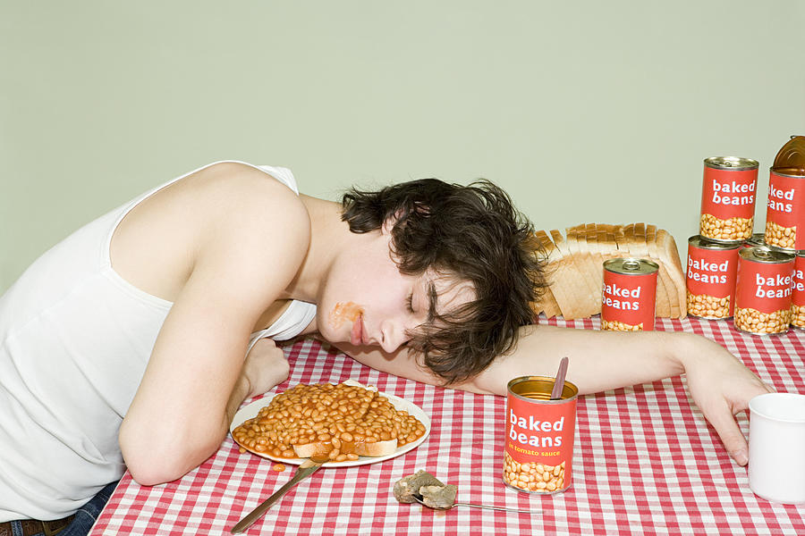 Teenage boy sleeping near a plate of beans Photograph by Image Source