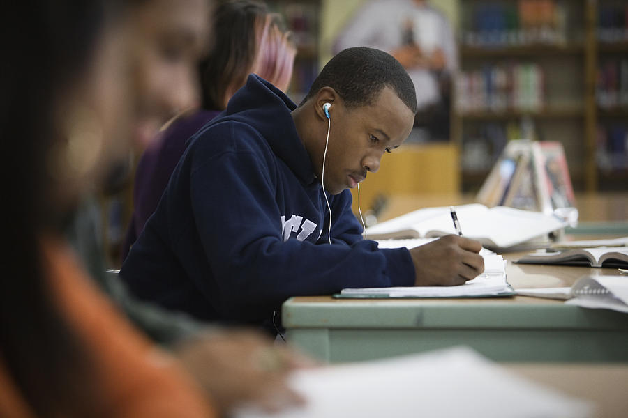 Teenage boy studying in school library Photograph by Hill Street Studios