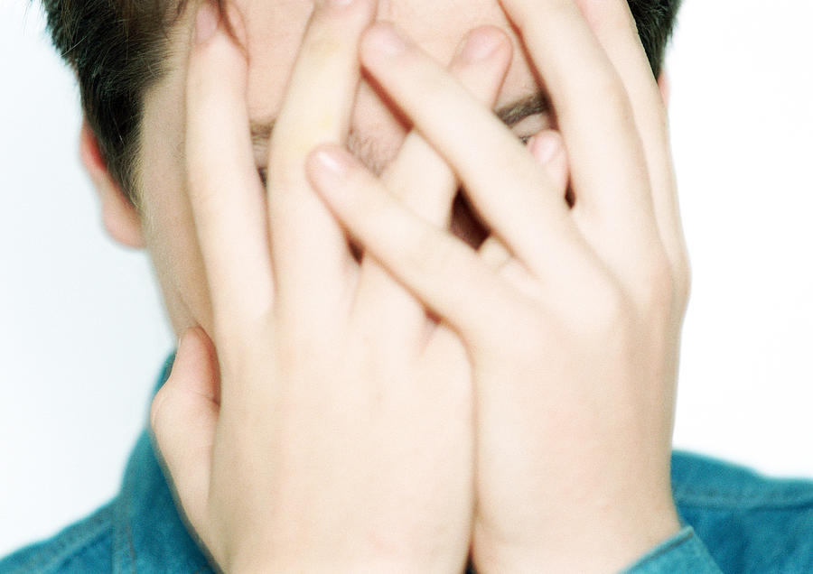 Teenage boy with hands covering face, close-up Photograph by Isabelle Rozenbaum
