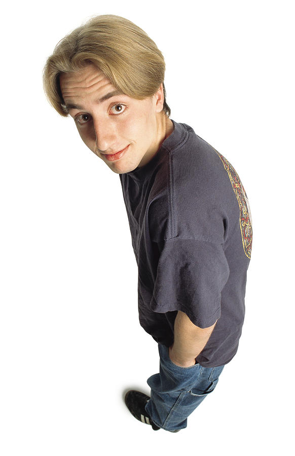 Teenage Boy With Longer Dark Blonde Hair And Brown Eyes Wearing A Purple T-shirt Blue Jeans And Black Soccer Shoes Looks Up Into The Camera With Big Eyes And A Slight Smile And Raises His Eyebrows Photograph by Photodisc