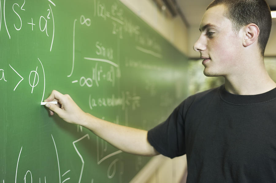 Teenage boy writing on chalkboard Photograph by Jupiterimages, Brand X Pictures