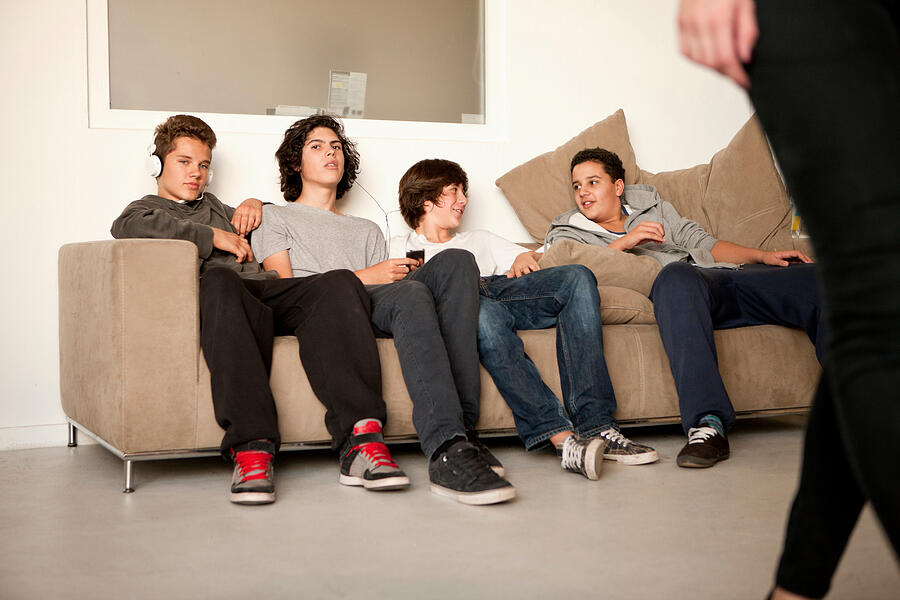 Teenage boys sitting on sofa Photograph by Cultura RF/Marcel Weber