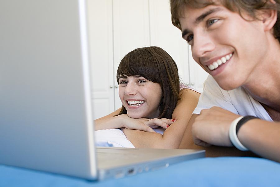 Teenage couple working on laptop Photograph by Image Source