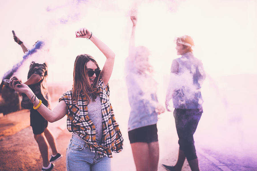 Teenage friends having fun with smoke bombs in city streets Photograph by Wundervisuals