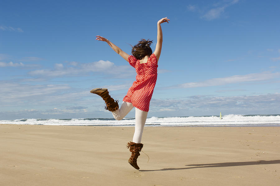 Teenage girl (16-17) dancing on beach, rear view Photograph by Bec Parsons