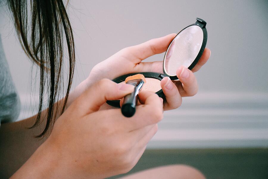 Teenage girl applying make-up Photograph by JuliaK