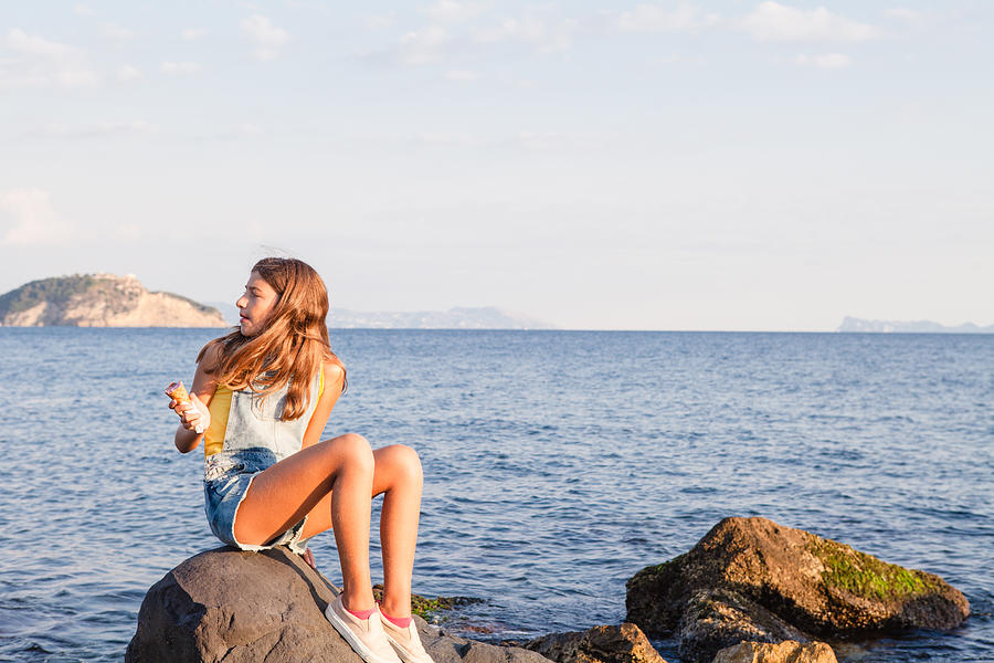 Teenage girl enjoys icecream at seaside Photograph by Angelafoto
