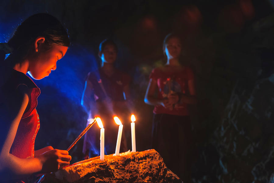 Teenage girl lighting candle, Tham Piu cave, Xieng Khuang Province, Laos Photograph by Cultura RM Exclusive/Stuart Westmorland