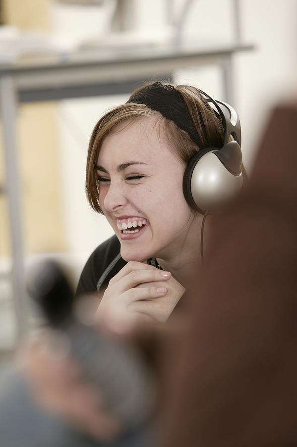 Teenage girl listening to headphones laughing Photograph by Comstock Images